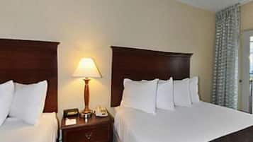 Habitación de hotel con dos camas, una mesita de noche con lámpara y una ventana con cortinas.