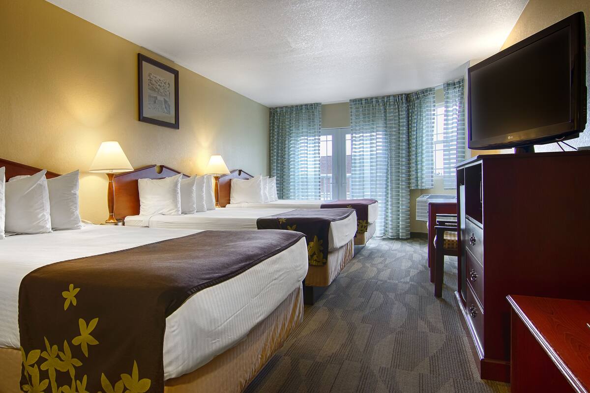 Een hotelkamer met twee bedden, een televisie, een bureau en een raam met gordijnen.