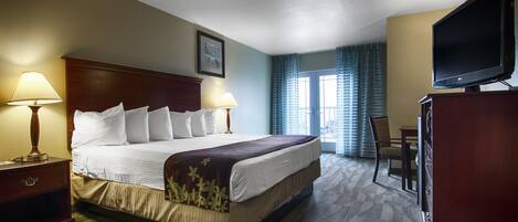 A hotel room with a large bed, two bedside lamps, a television, a desk, and a chair.
