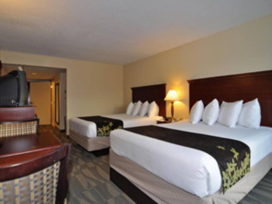 Quarto de hotel com duas camas, uma escrivaninha e uma televisão.