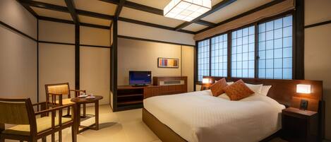 Habitación de hotel con una cama grande, televisor, escritorio y una silla.
