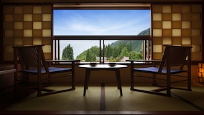 A traditional Japanese room with tatami flooring, a low table, and two wooden chairs. - Omiya Ryokan (Yamagata)