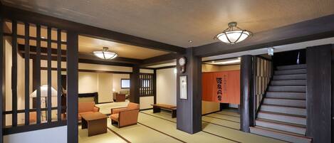 A traditional Japanese room with tatami flooring, a low table, cushions, and a sliding door.