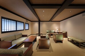 Una habitación tradicional japonesa con suelo de tatami, muebles de madera bajos y puertas correderas.