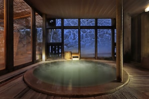 Un jacuzzi con un fondo de pared de piedra y suelo de madera.