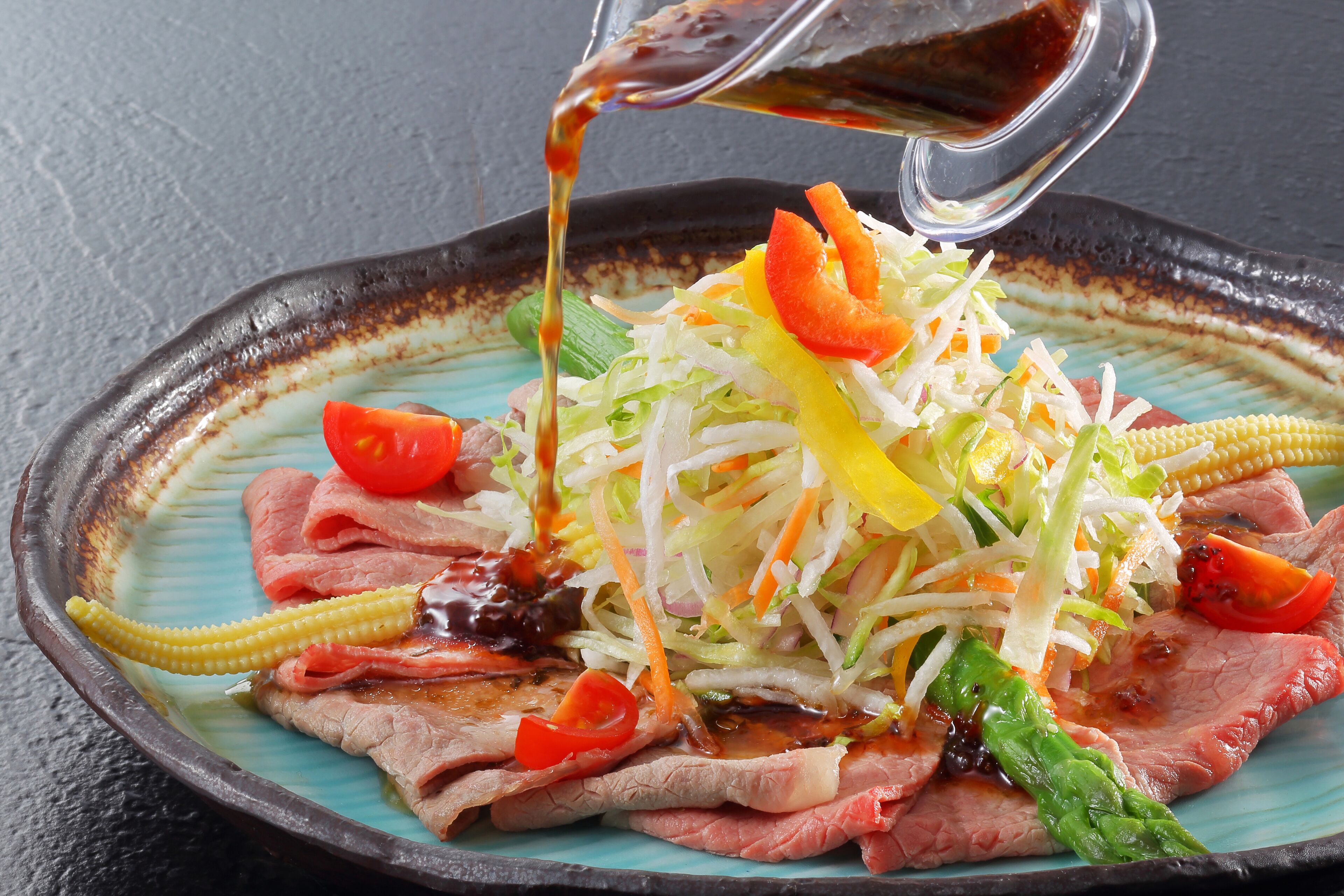A plate of sliced meat with vegetables and sauce.