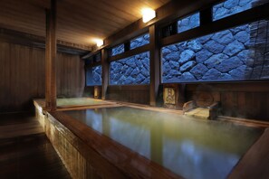 A traditional Japanese onsen with wooden interiors and stone walls. - Omiya Ryokan (Yamagata)
