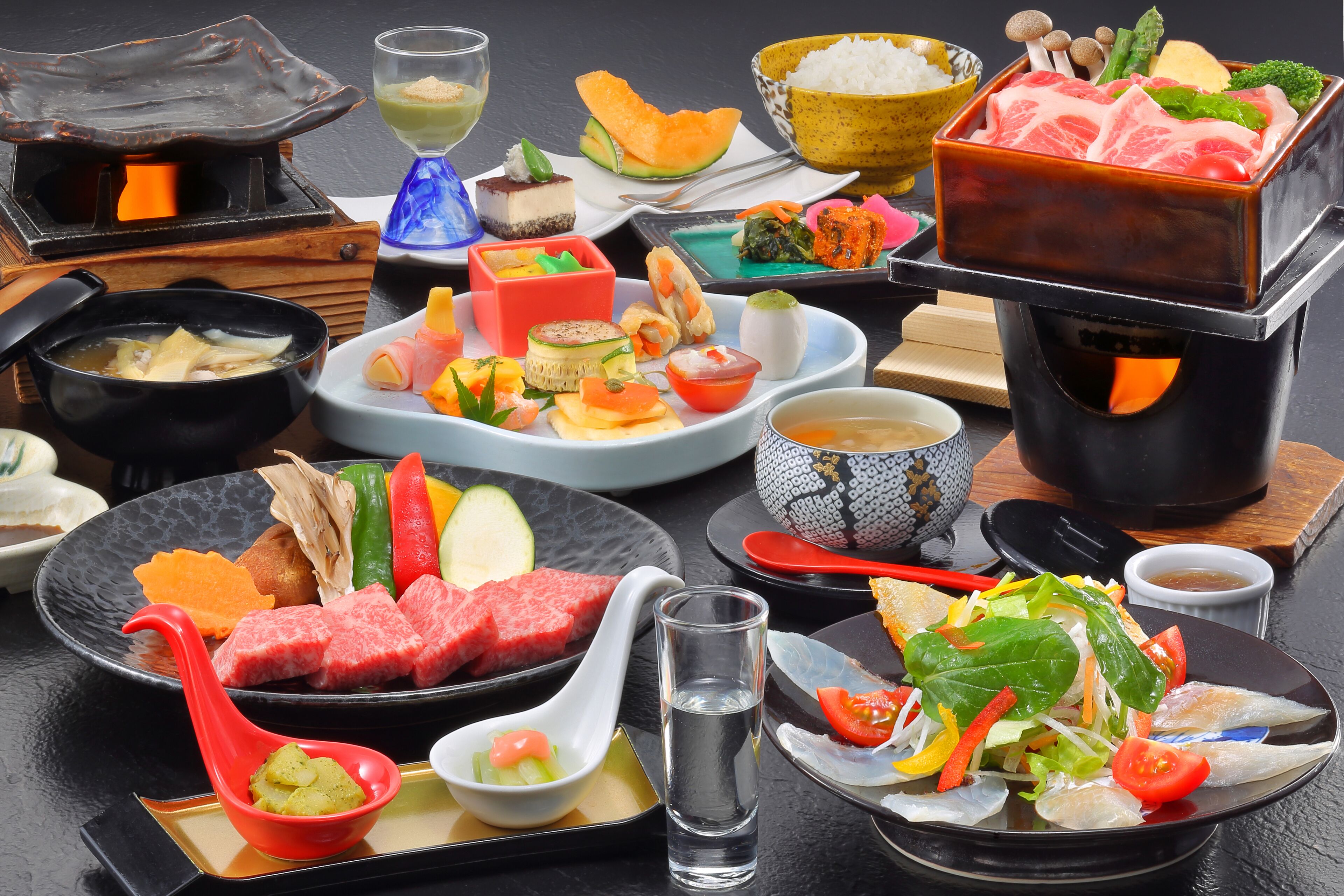 A variety of dishes and a hot pot setup on a table.