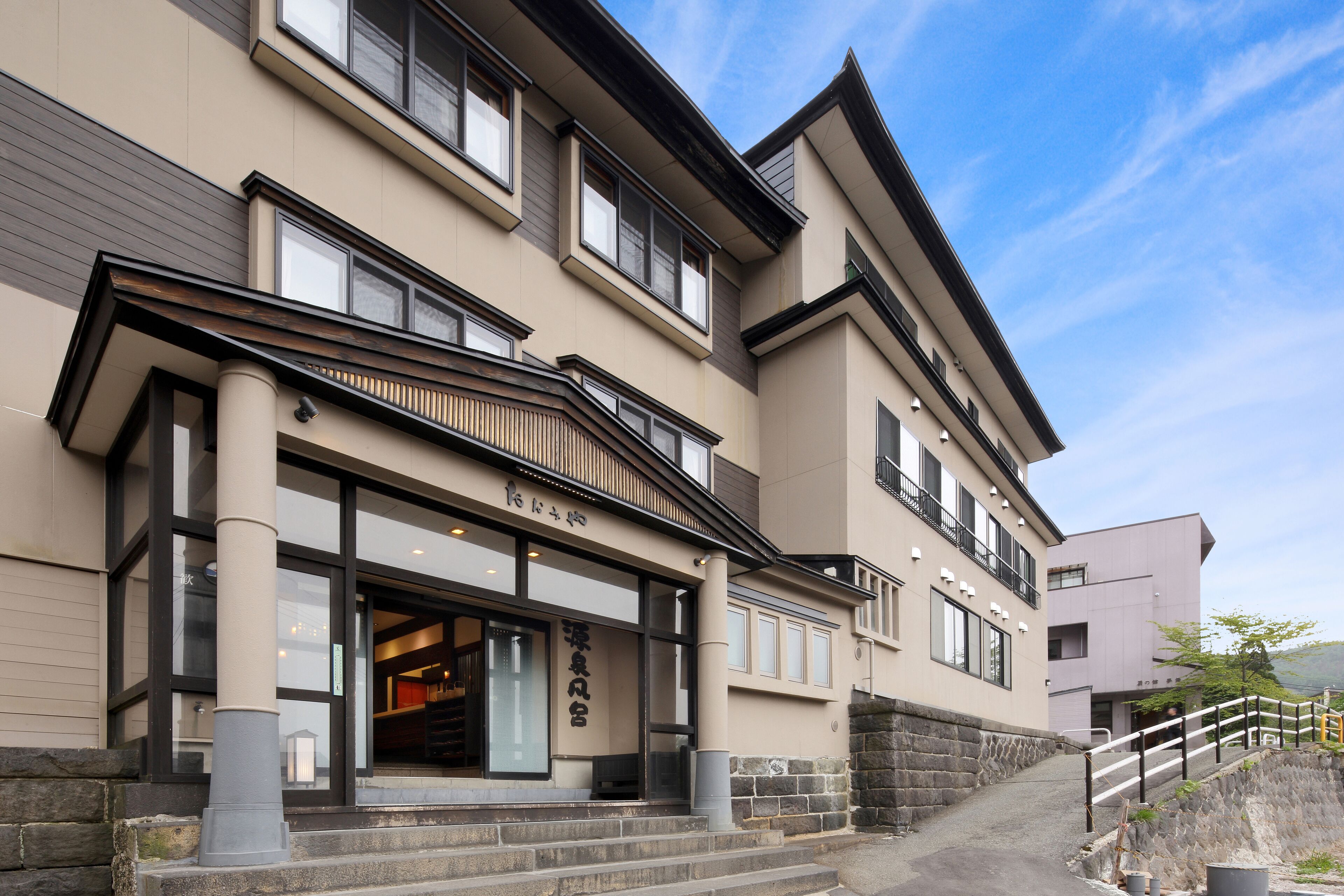 A multi-story building with a beige facade, large windows, and a stone base.