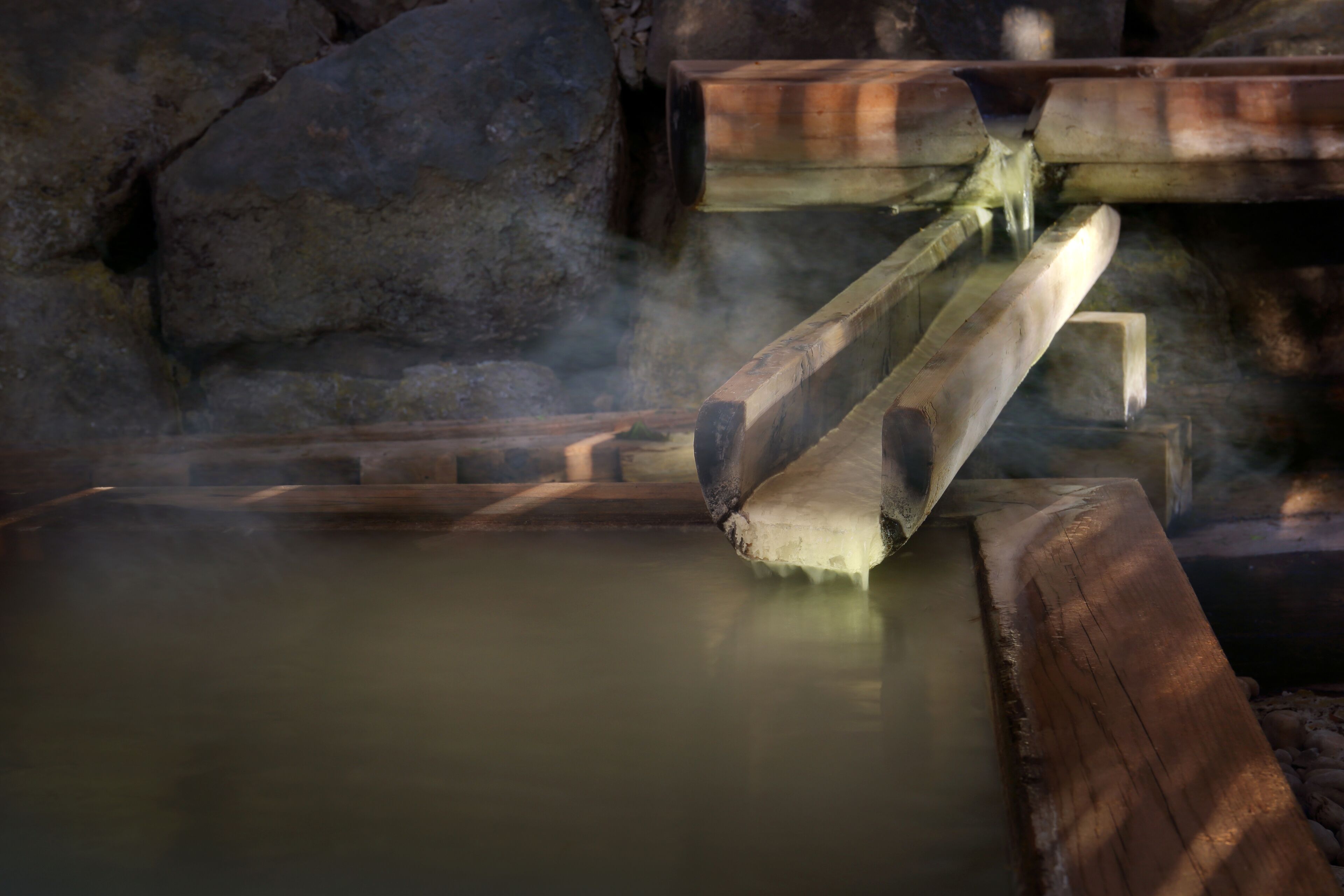A hot spring area with wooden benches and a stone wall.