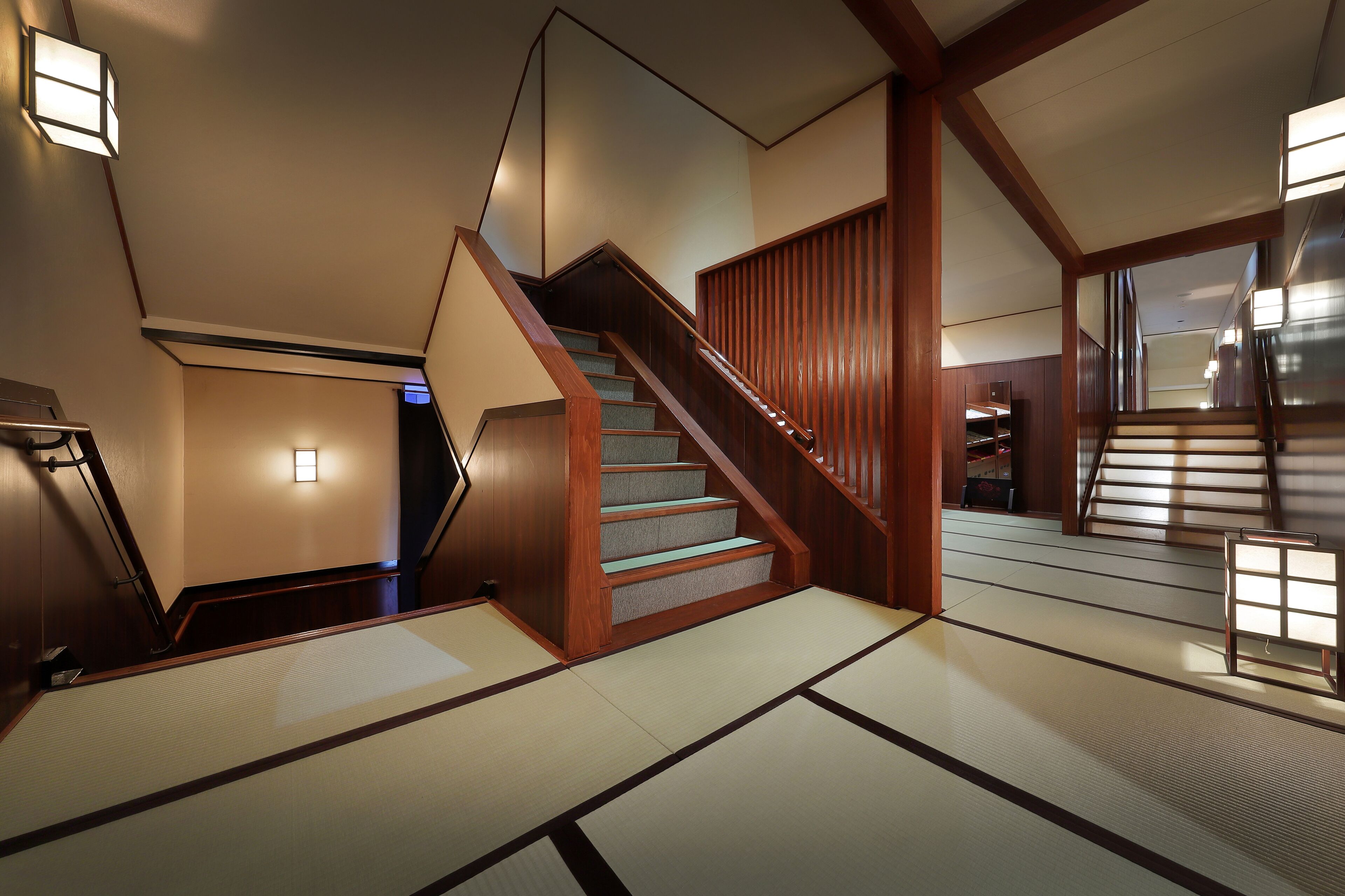 Un interior japonés tradicional con suelo de tatami, una escalera de madera y paneles shoji.