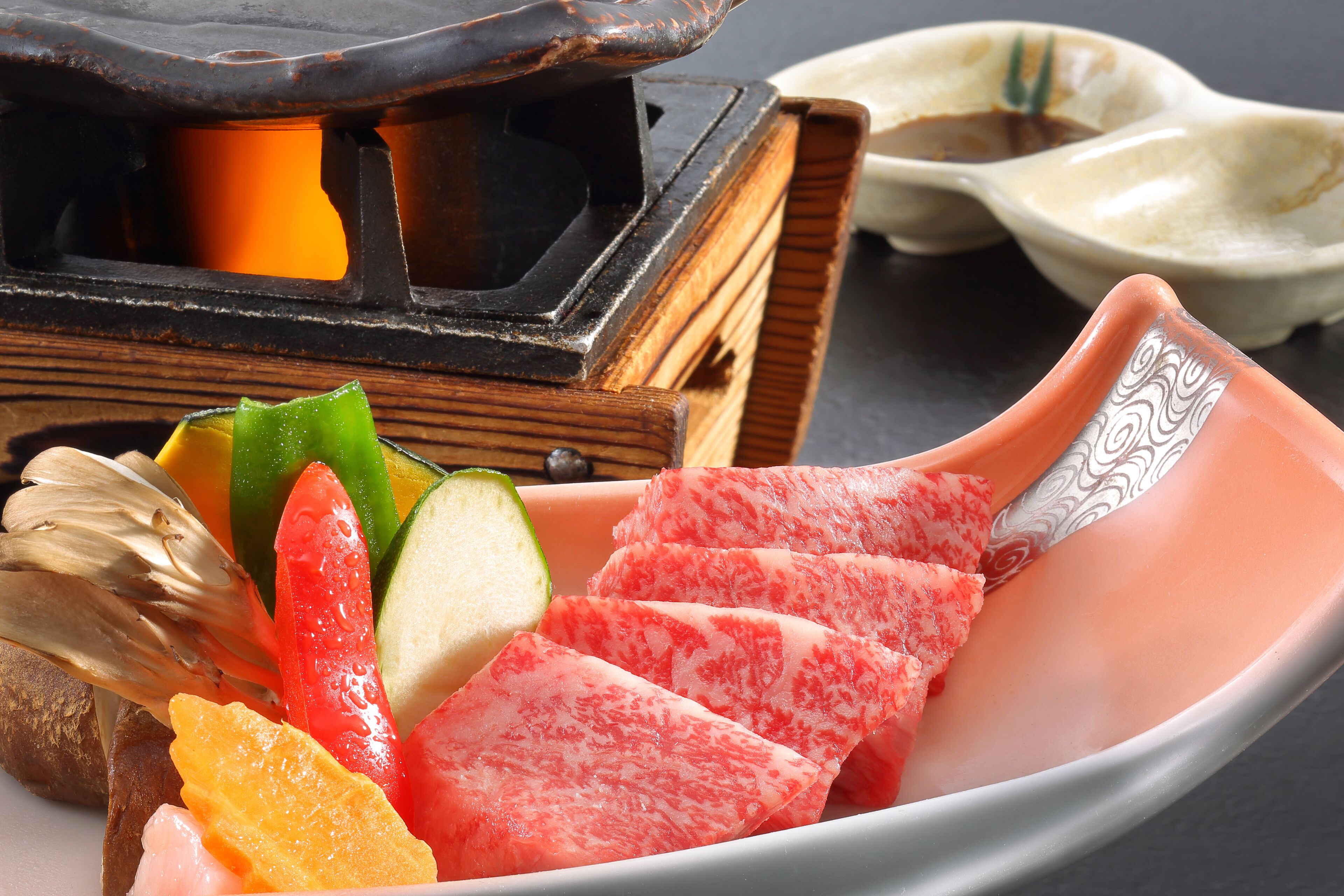 A wooden table with a ceramic dish containing sliced watermelon and vegetables.