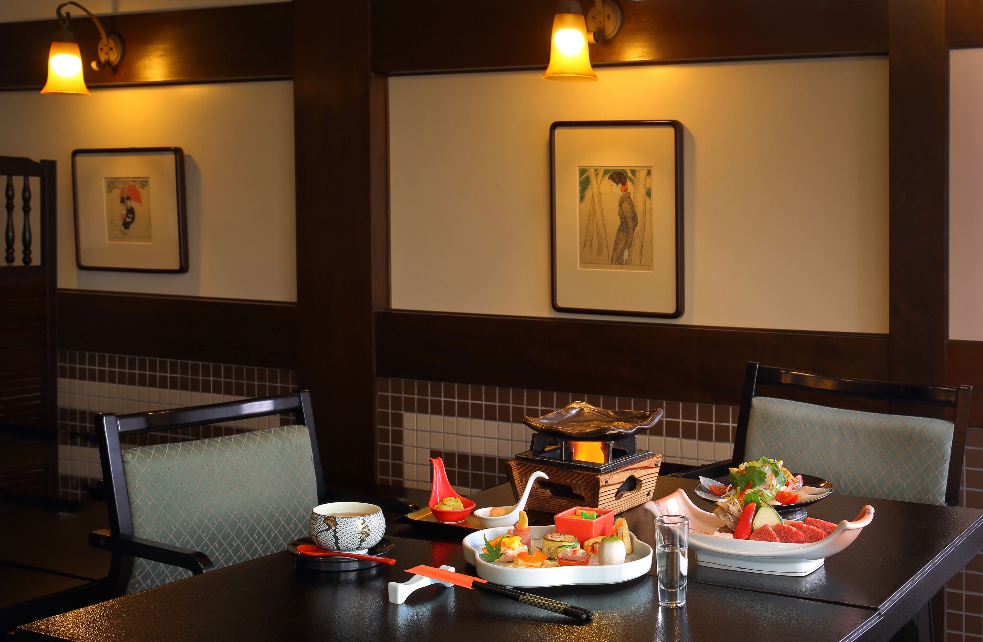 Une table de restaurant dressée avec différents plats, une théière et un service à thé japonais traditionnel.