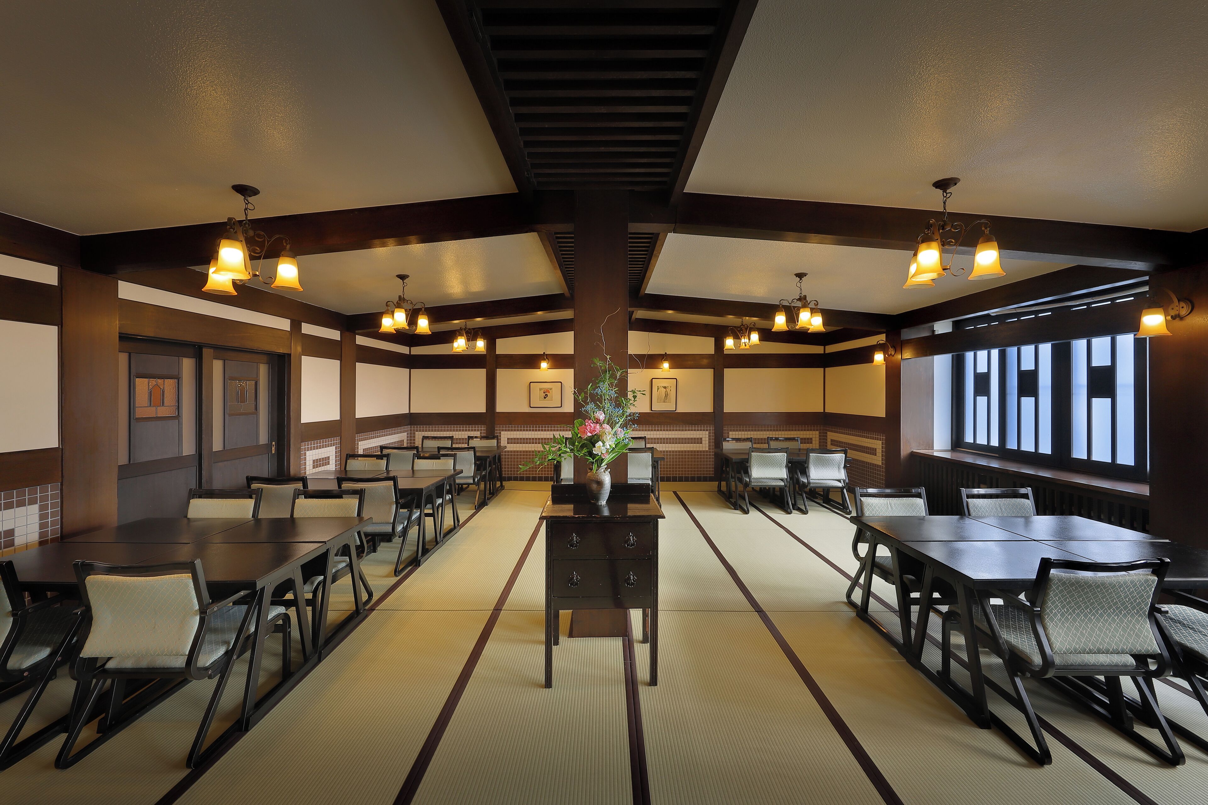 A conference room with multiple tables and chairs, a central decorative vase, and ceiling lights.