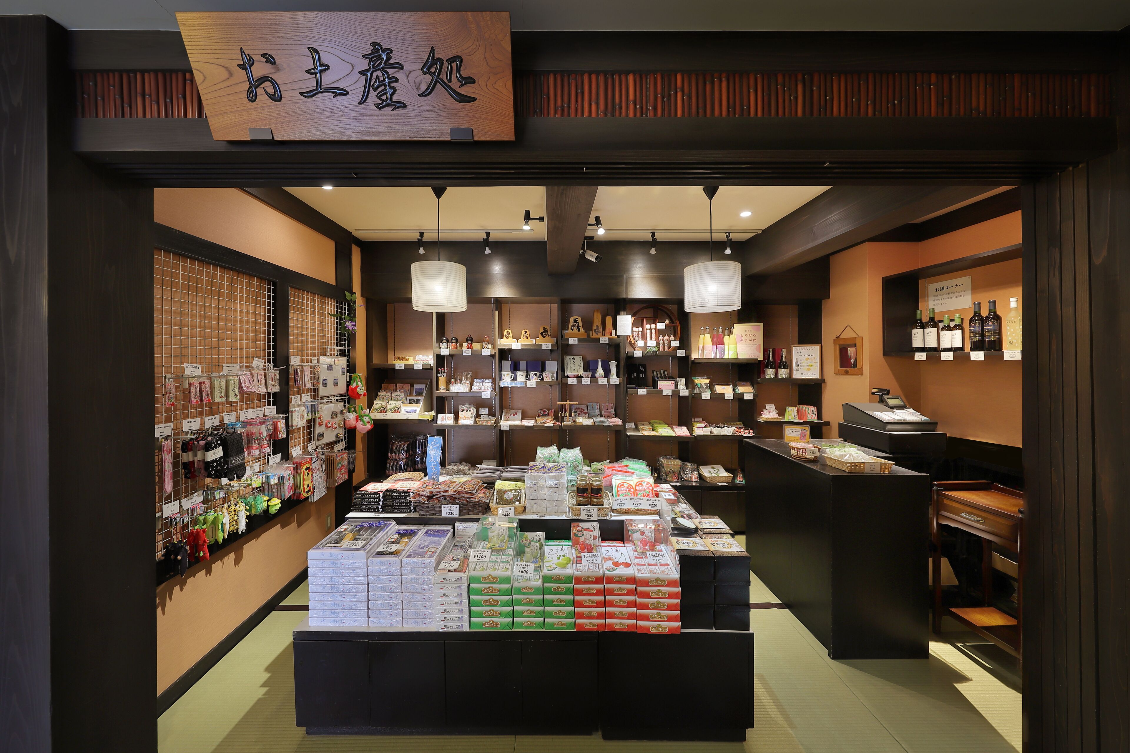 A store with shelves stocked with various products, a display counter with boxes, and hanging items on the walls.
