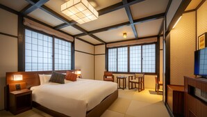 A hotel room with a large bed, bedside tables, a desk, and chairs. - Omiya Ryokan (Yamagata)