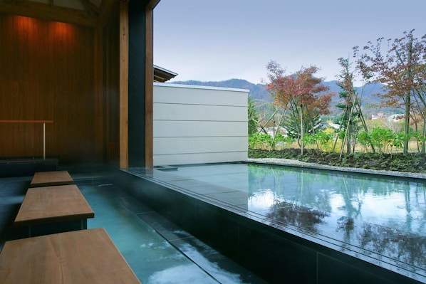 Área de piscina interior moderna com bancos de madeira e vista para árvores e montanhas.