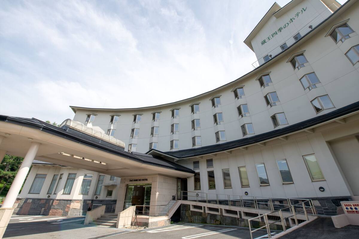 Un hotel con fachada curva, varias ventanas y un área de entrada cubierta.