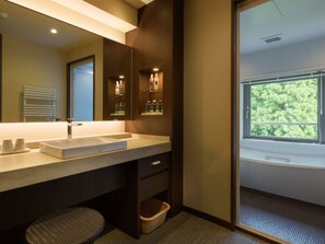 Un baño moderno con un espejo grande, un lavabo y una ventana con vistas a árboles.