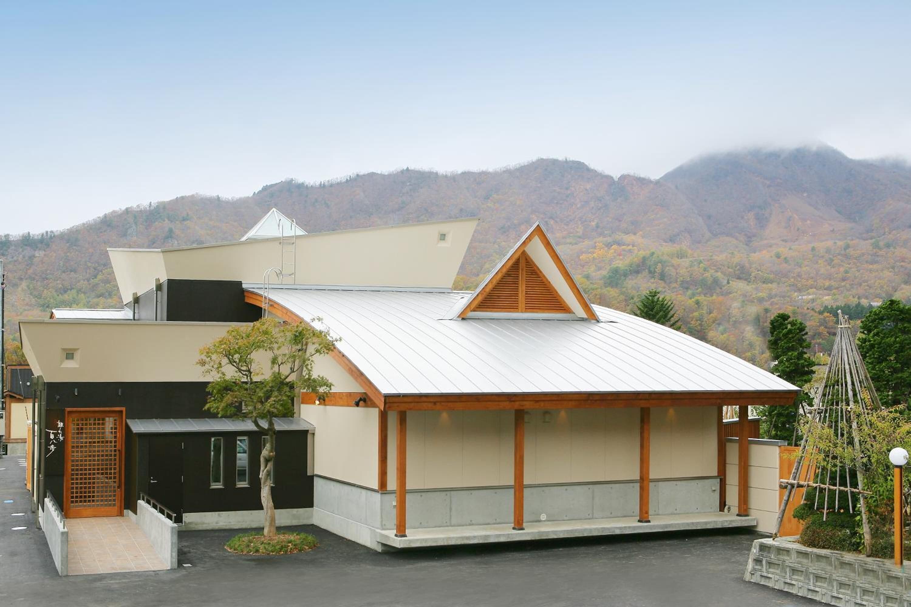 A modern building with a sloped roof, a small porch, and a view of a mountainous landscape.