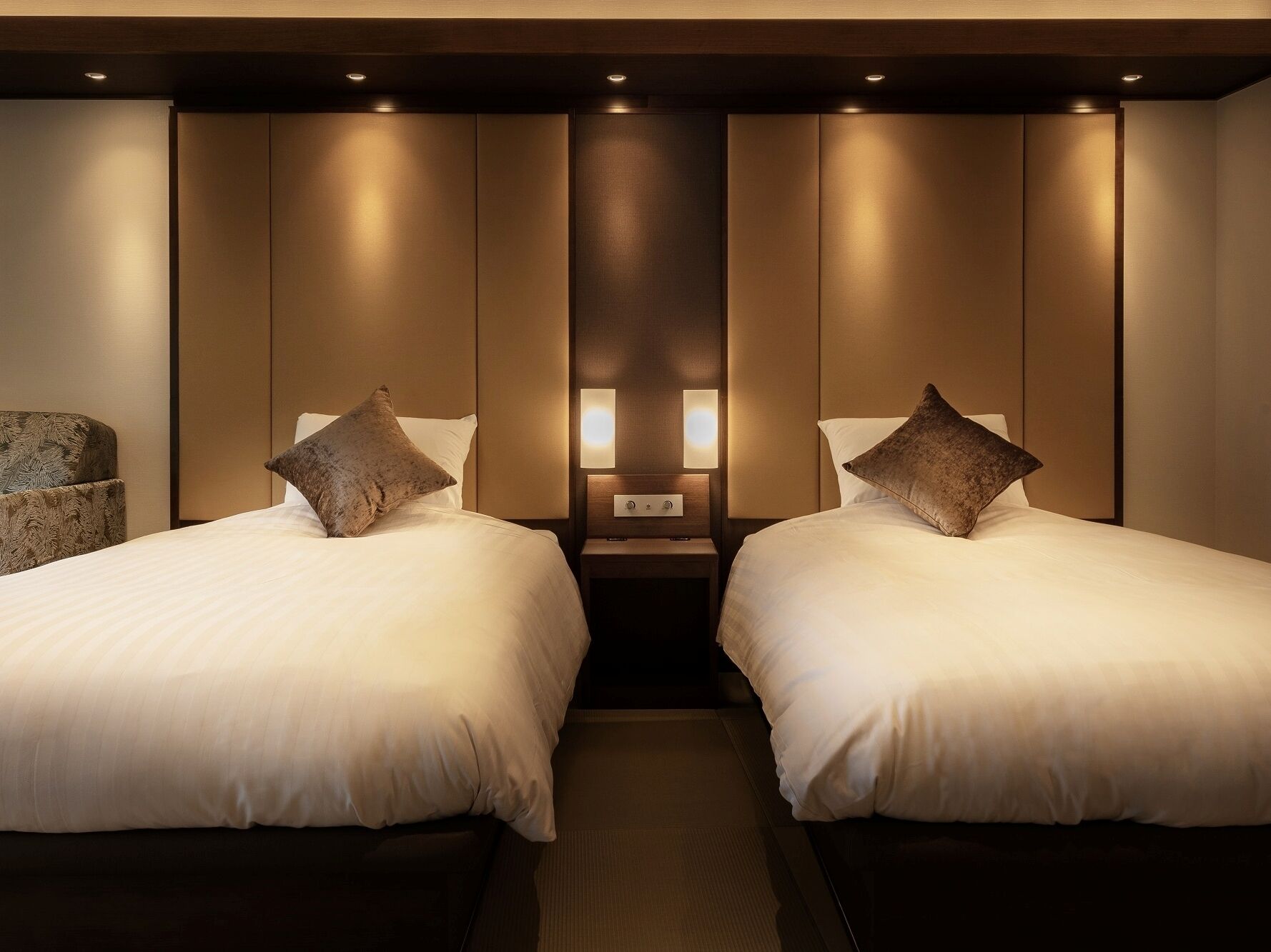 Une chambre d’hôtel avec deux lits, chacun étant équipé d’un oreiller et d’une table de chevet avec une lampe.
