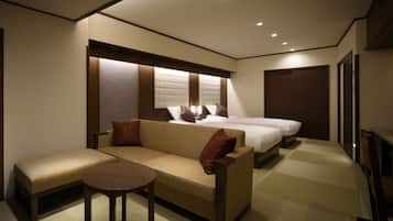 A hotel room with a sofa, a small table, two beds, and a wardrobe.