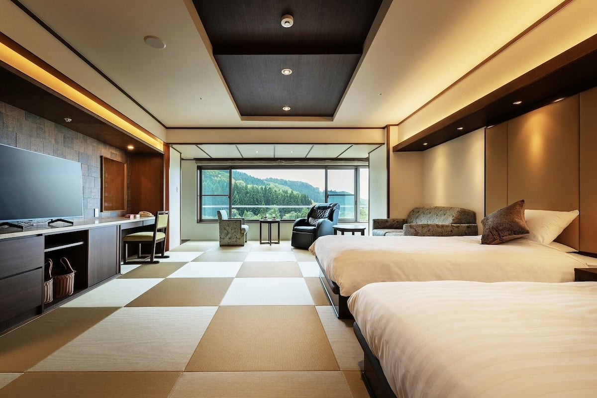 Habitación de hotel moderna con una cama grande, un escritorio y vistas a un paisaje montañoso.