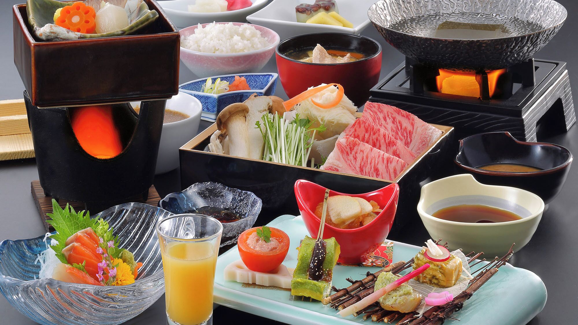 Verschiedene japanische Gerichte, darunter Sushi, Sashimi und Tempura, serviert auf einer Platte mit Reis- und Suppenschalen.