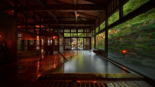 Un interior espacioso con suelo de madera, ventanas amplias y vistas a un jardín rocoso.