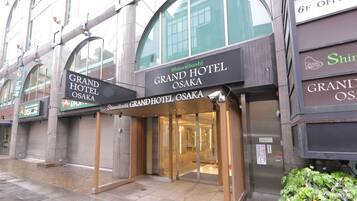 The Grand Hotel Osaka entrance with a glass door and a sign above it.