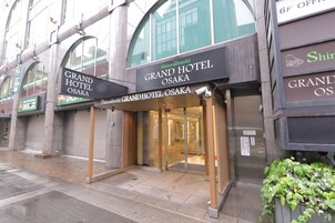 The Grand Hotel Osaka entrance with a glass door and a sign above it.