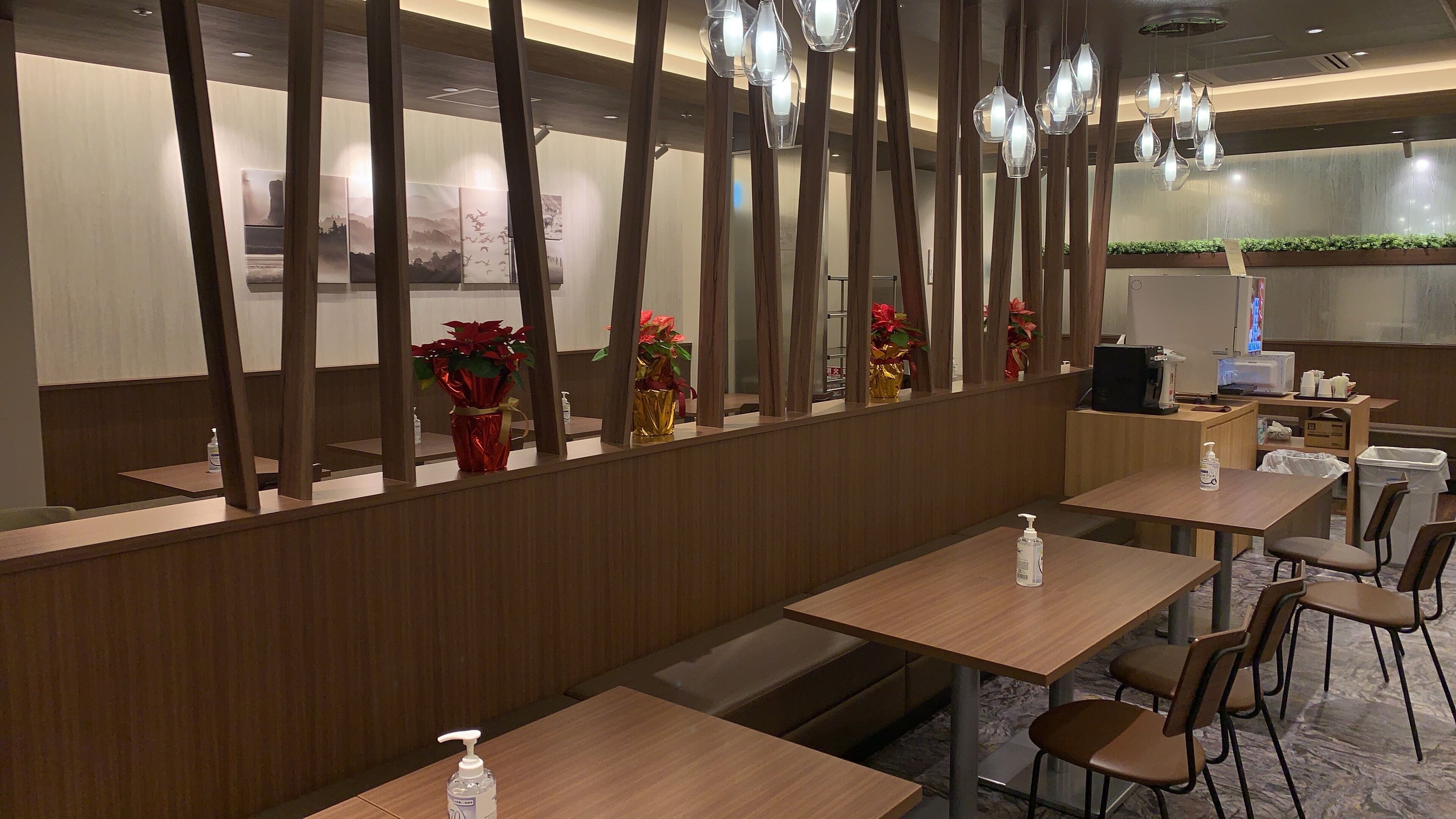 Ein modernes Restaurant mit Holztischen und -stühlen, dekorativen Vasen und Pendelleuchten.