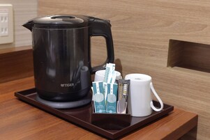 A coffee maker, a white mug, and a tray with coffee pods on a wooden counter.