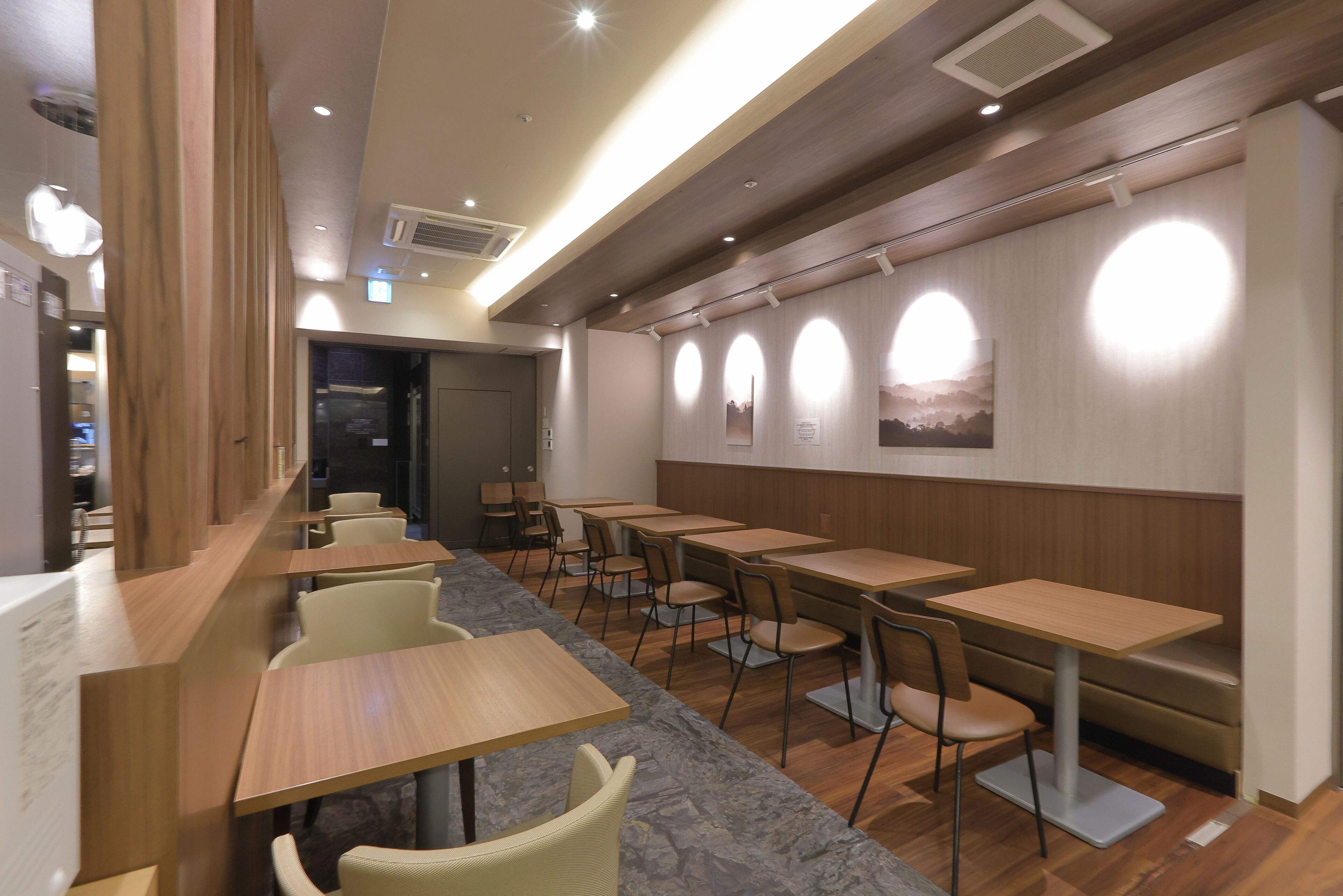 Un restaurante con mesas y sillas de madera, una barra de mármol y una pared con ventanas circulares.