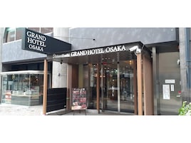 The entrance to Grand Hotel Osaka with a clear sign above the door and a menu board outside.