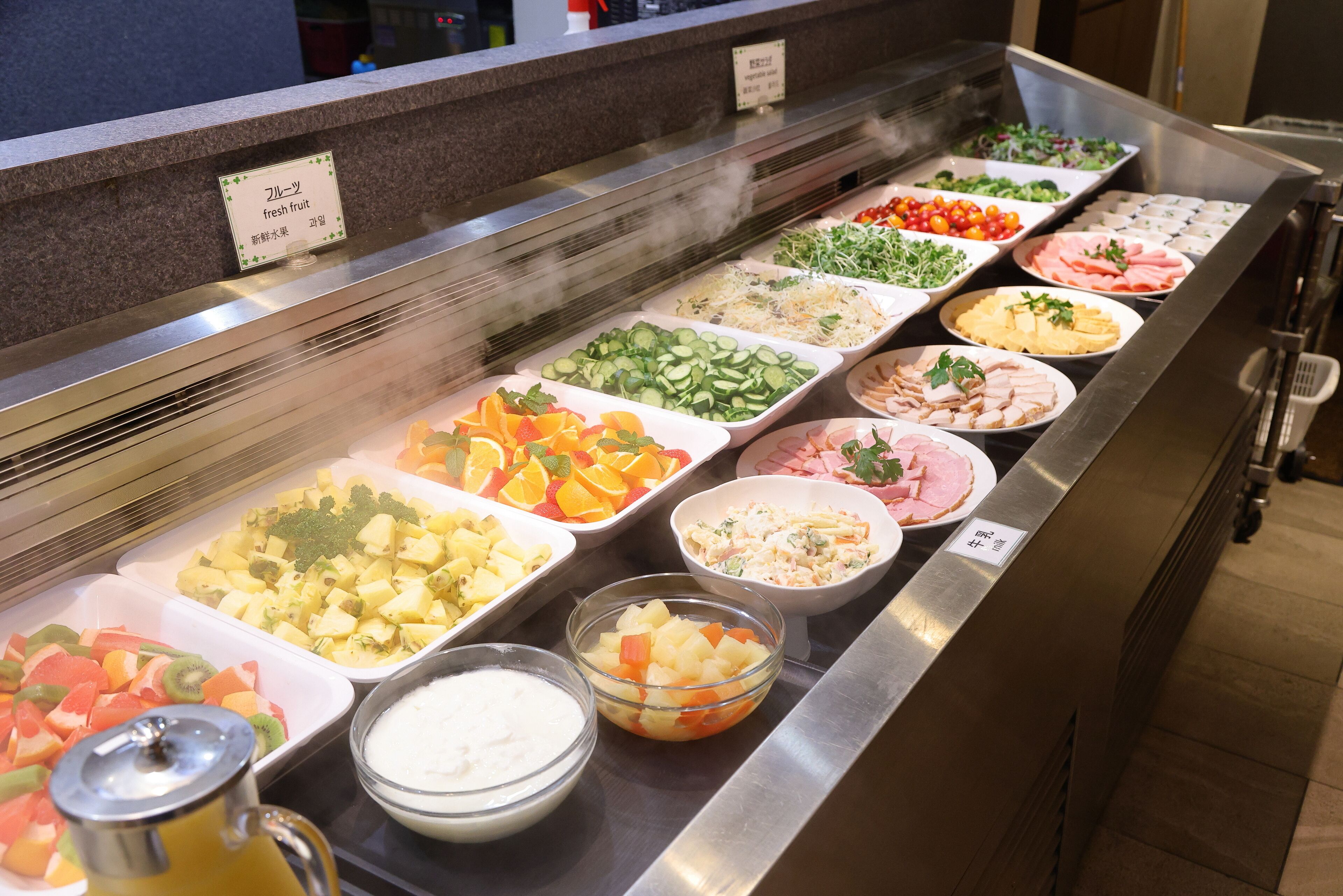A buffet with various food options including fruits, vegetables, and meats.