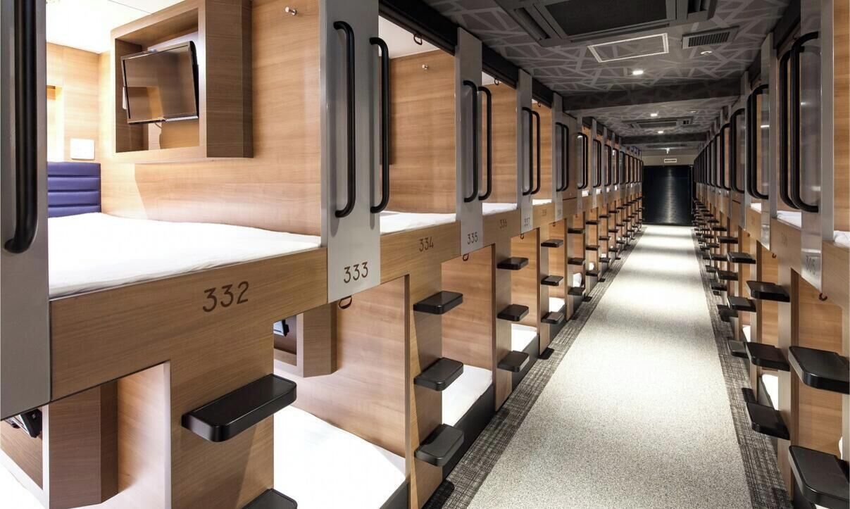 Un vagone ferroviario con divisori in legno, cuccette numerate e un corridoio centrale.