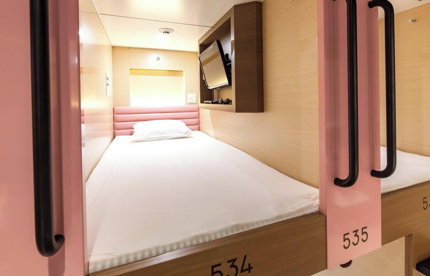 Una camera d'albergo con un letto, una televisione montata a parete e una porta con un numero.