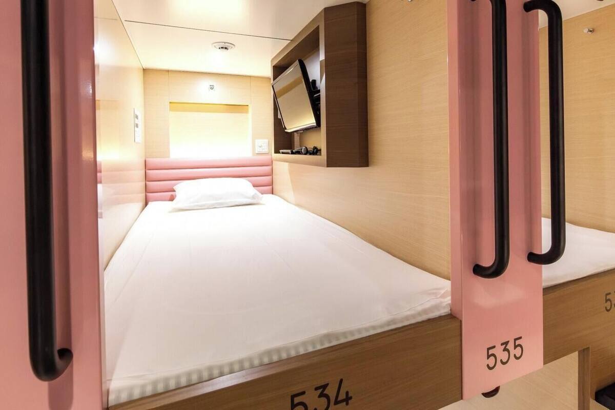 A hotel room with a bed, a television mounted on the wall, and a door with a number.