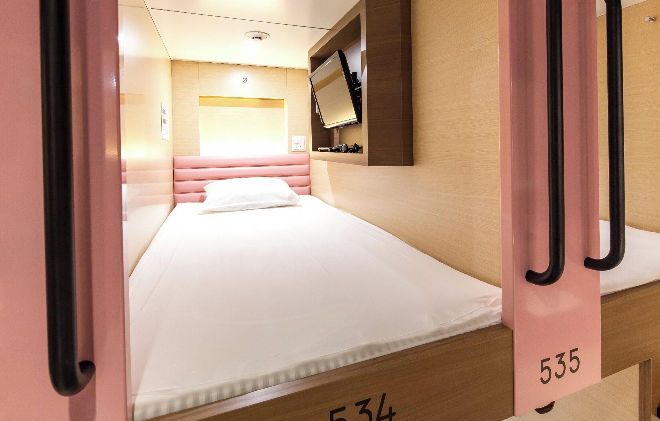 Une chambre d’hôtel avec un lit, un téléviseur fixé au mur et un numéro de chambre sur la porte.