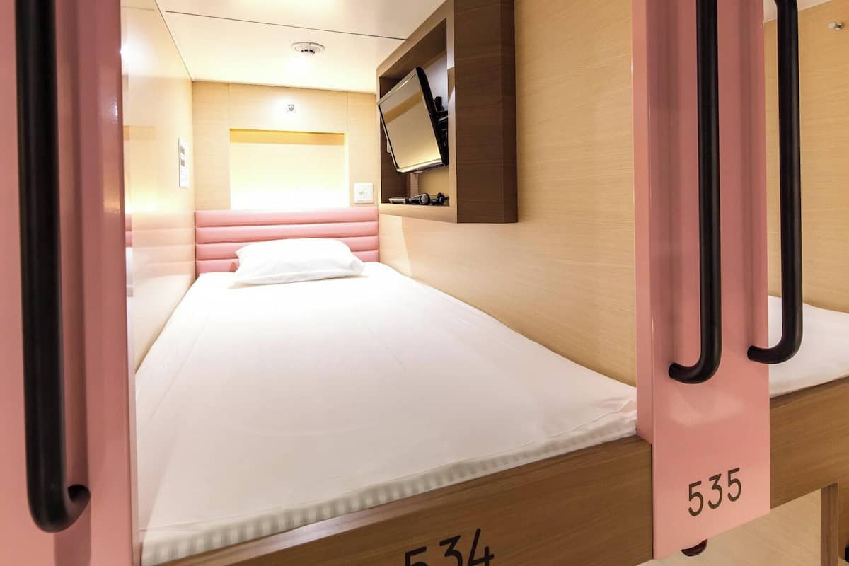 Une chambre d’hôtel avec un lit, un téléviseur fixé au mur et un numéro de chambre sur la porte.