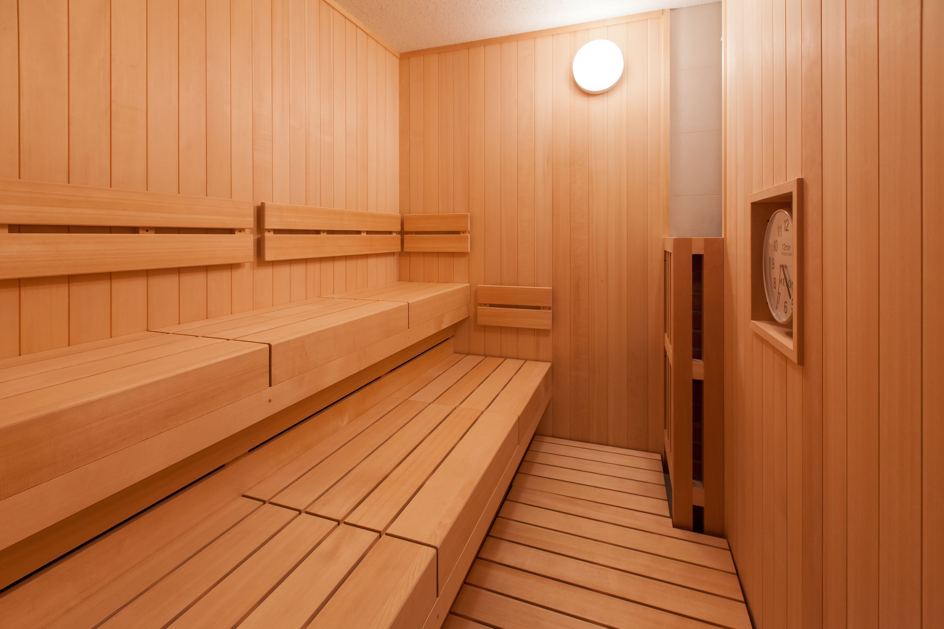 A wooden sauna with benches and a wall-mounted clock.