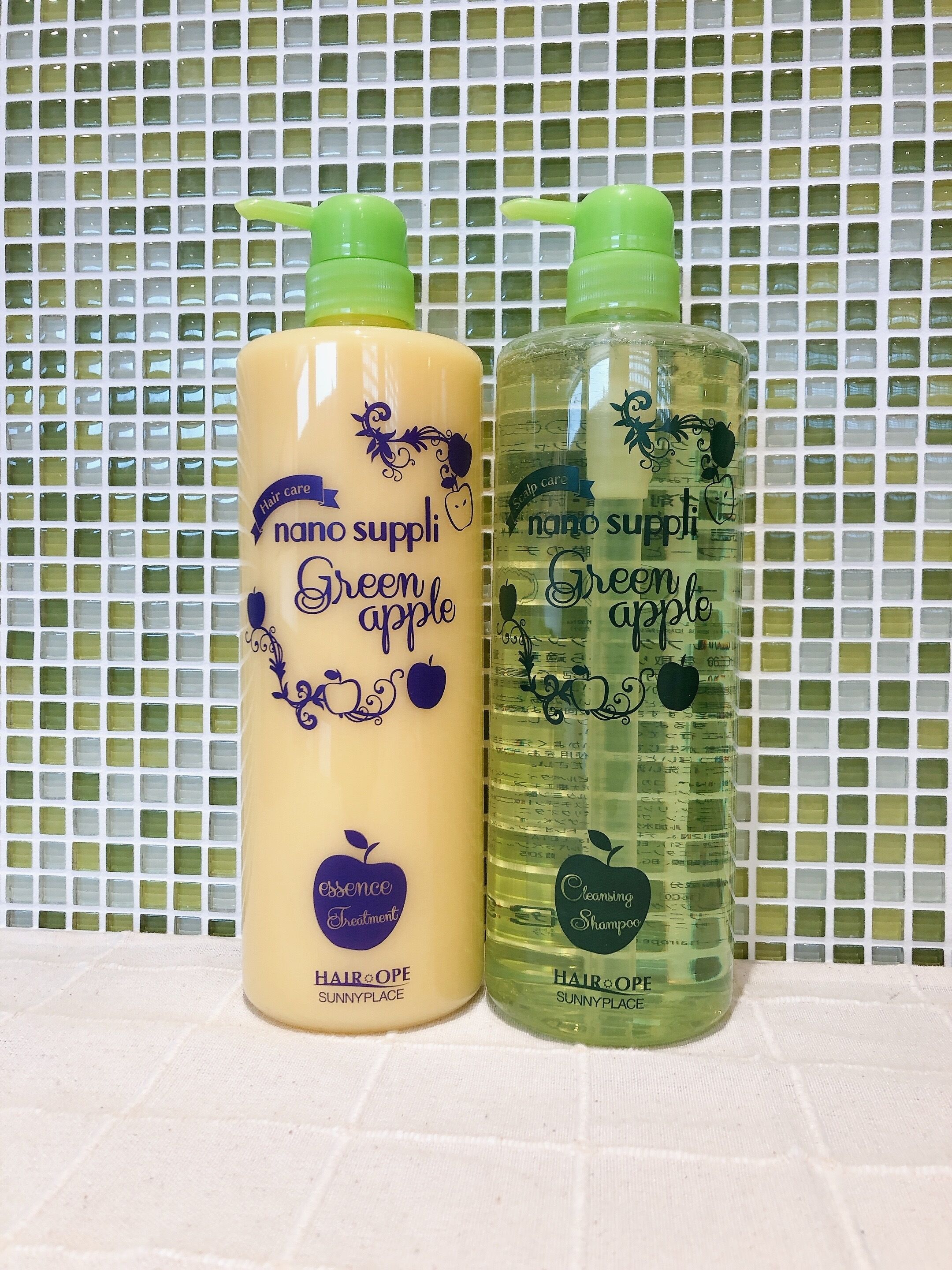Two bottles of hair care products labeled 'nano supp' and 'Green apple' against a tiled wall.