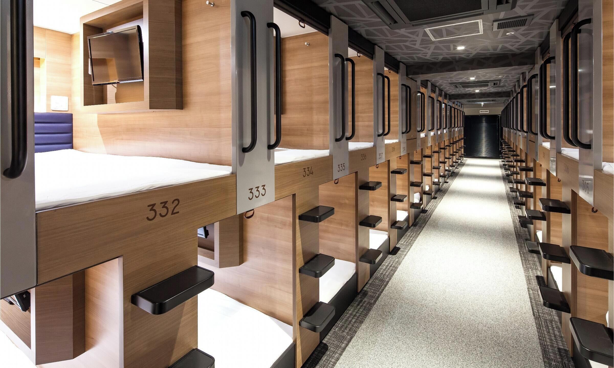 Une chambre d’hôtel moderne avec un plancher en bois, un lit portant un numéro et un couloir avec des compartiments numérotés.