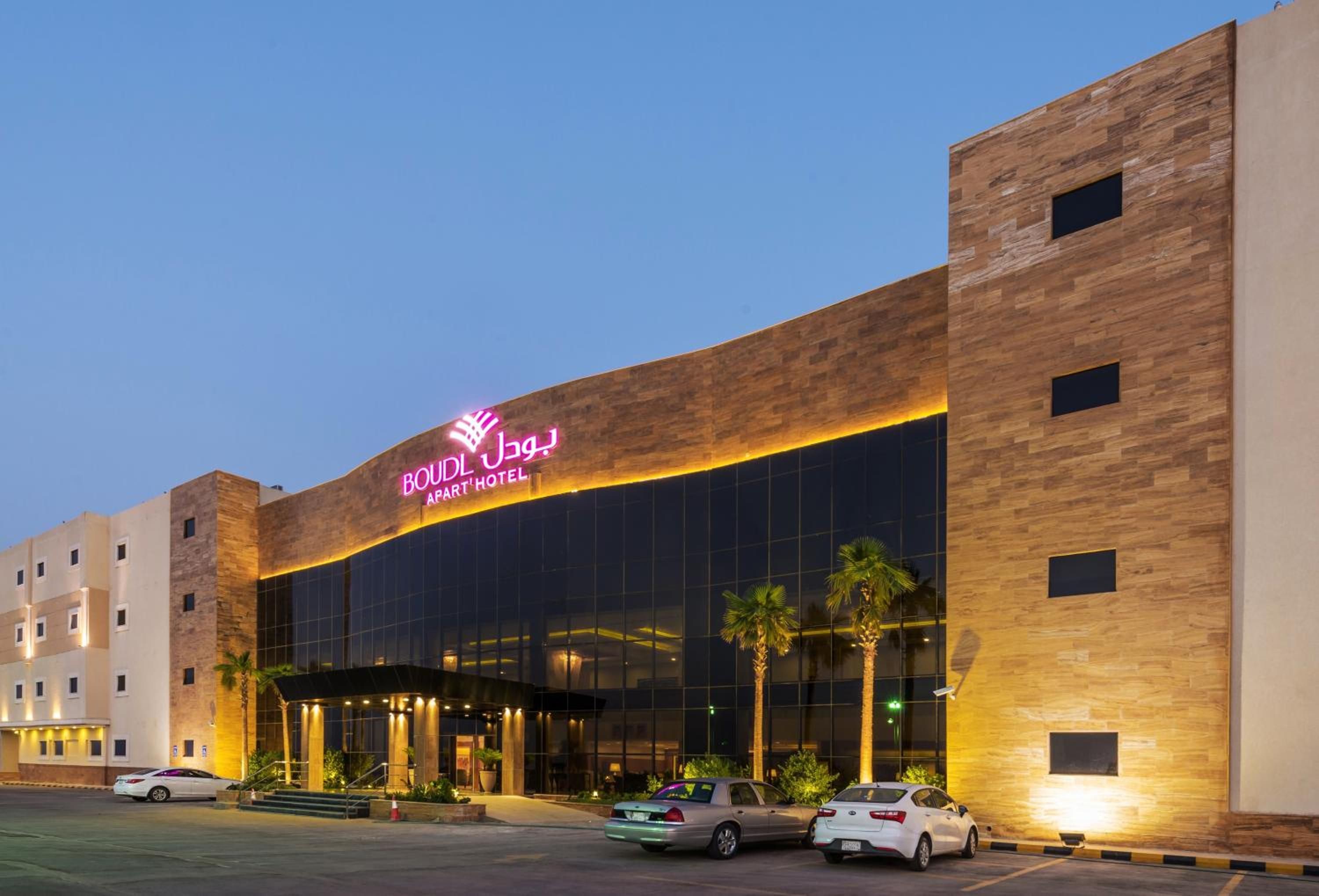 A hotel with a modern facade, large windows, and a prominent neon sign.
