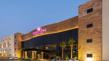 A hotel with a modern facade, large windows, and a prominent neon sign.