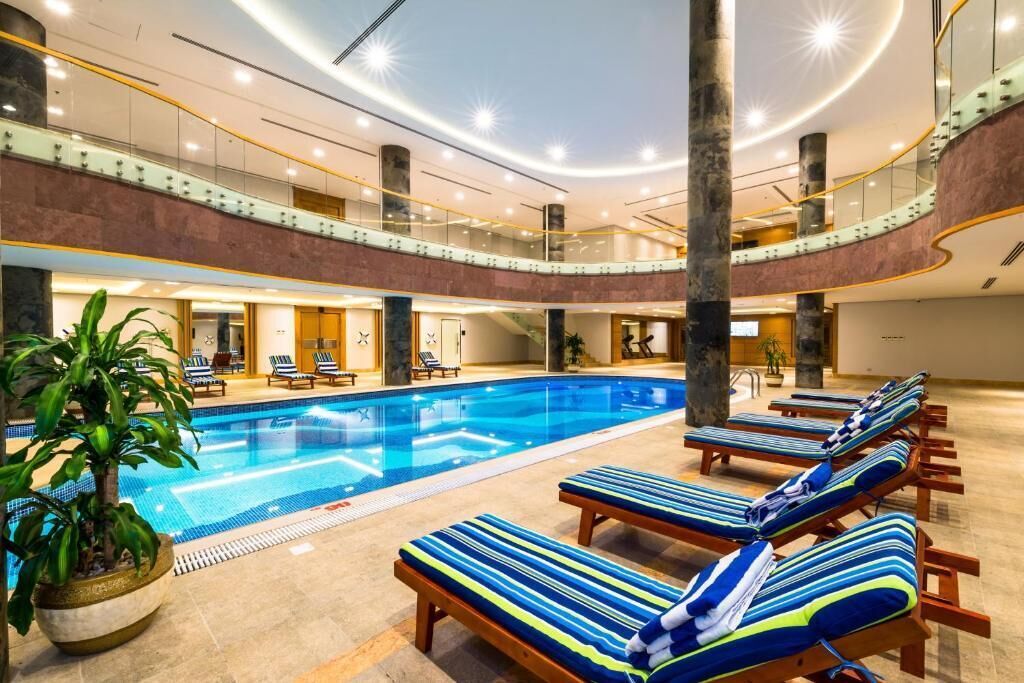 A multi-level indoor swimming pool with lounge chairs and a potted plant.