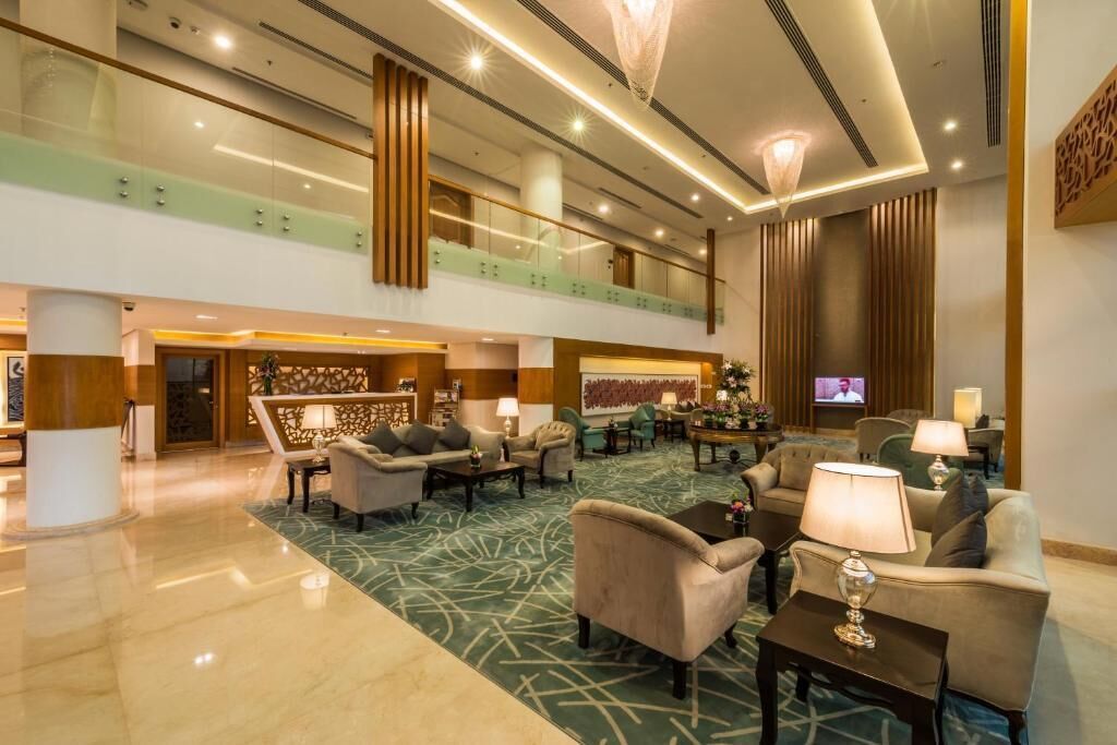 A spacious lobby with a high ceiling, multiple seating areas, and a television screen.