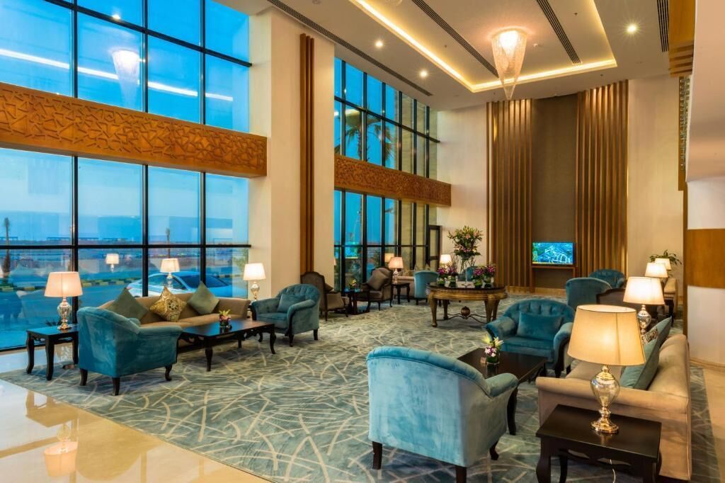 A hotel lobby with large windows, seating arrangements, and a television.