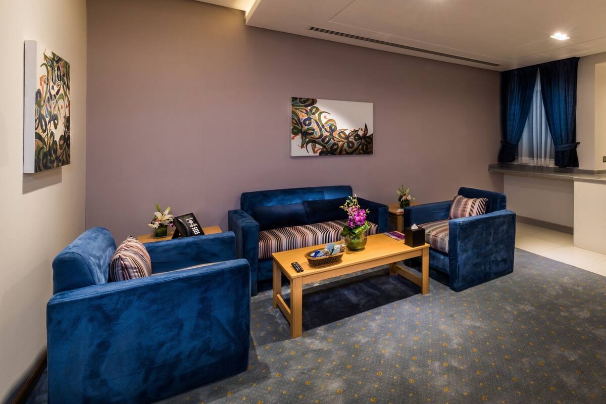 A modern living room with blue sofas, a coffee table, and artwork on the walls.